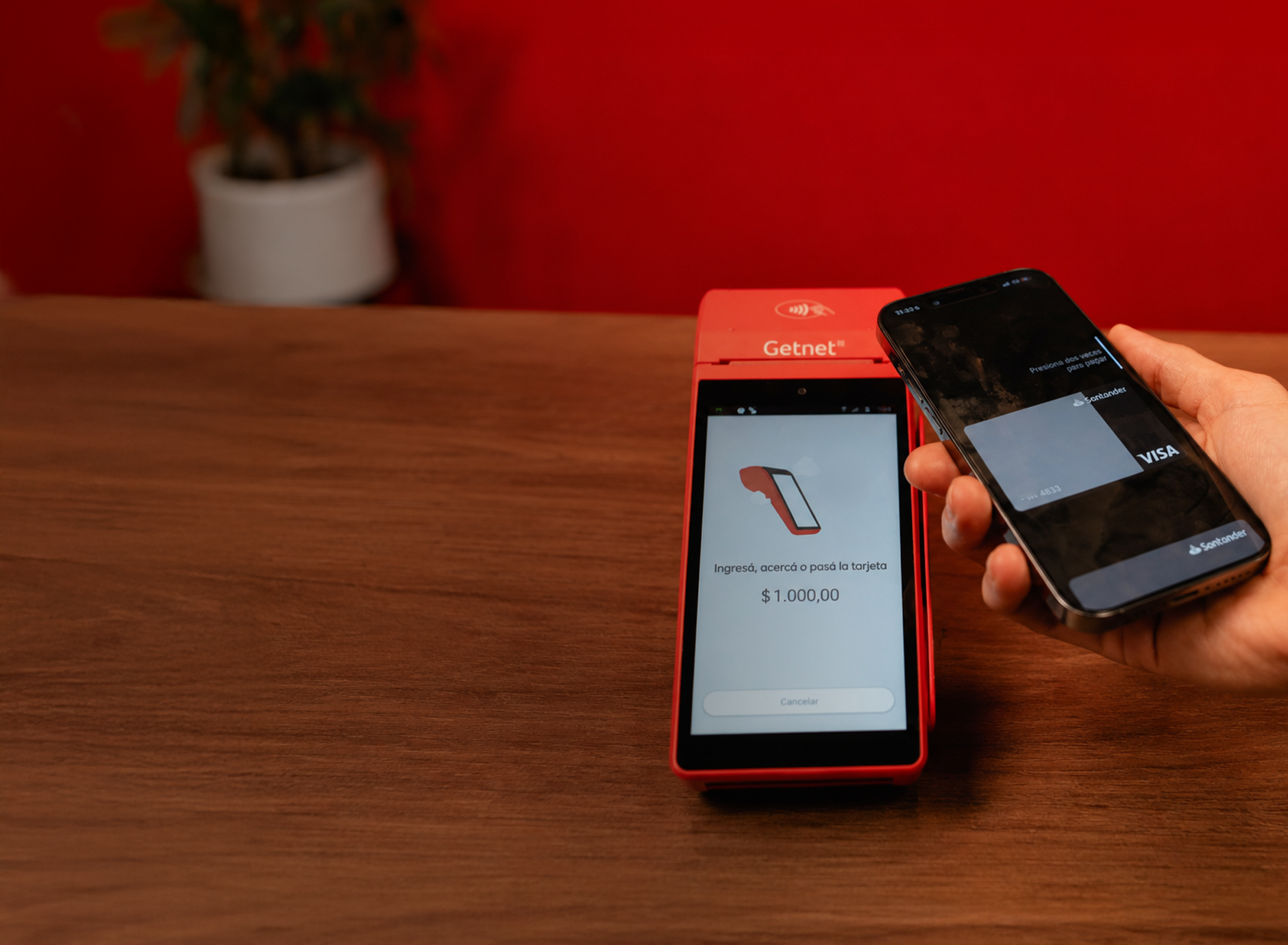 Teléfono celular realizando un pago sin contacto junto a una terminal de cobro Getnet sobre una mesa.