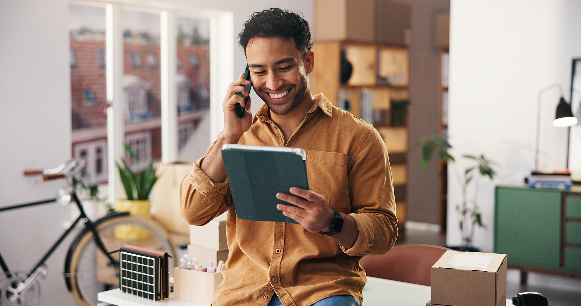 Persona hablando por teléfono mientras utiliza una tablet en un comercio