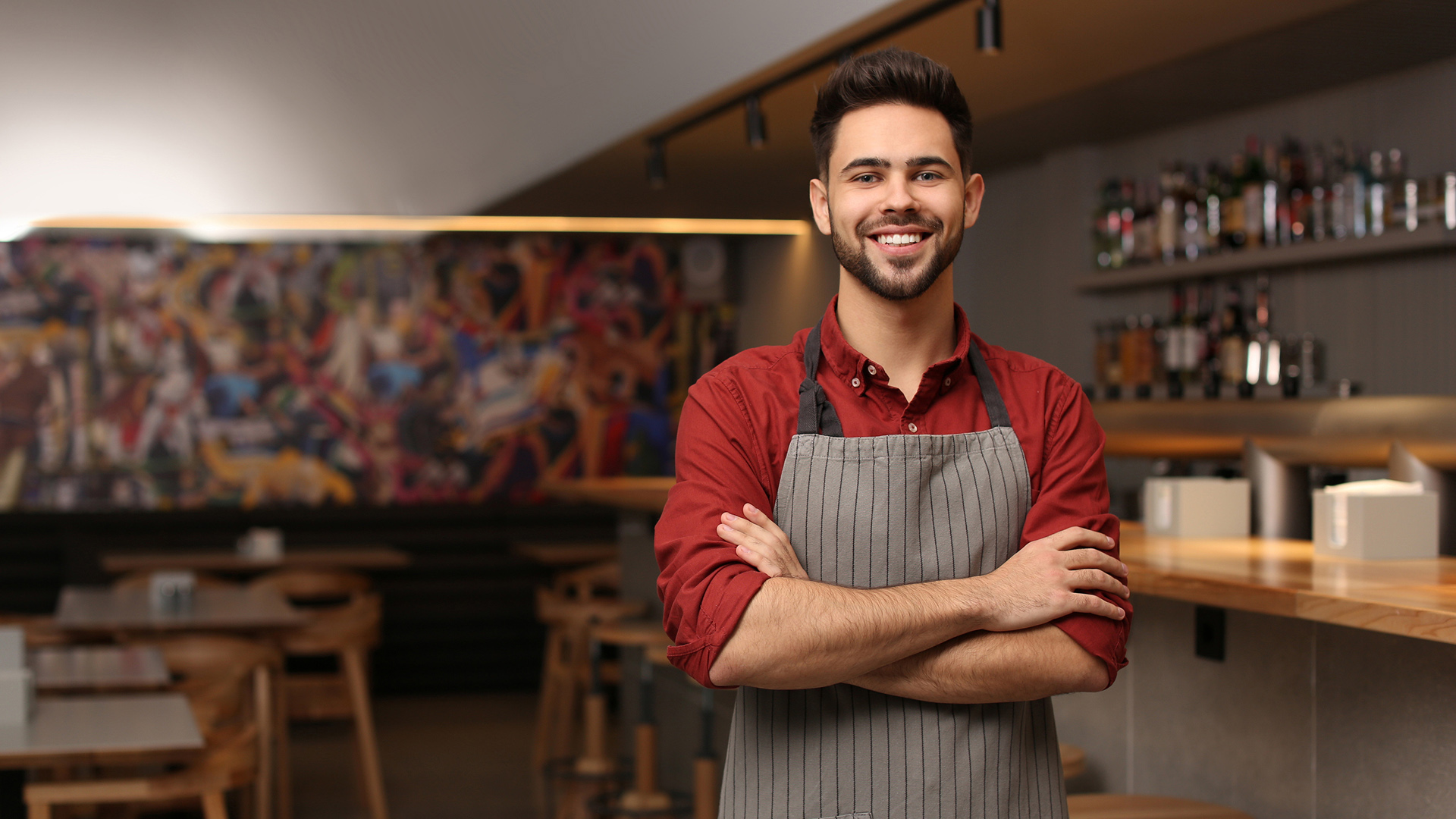 Empleado con brazos cruzados y delantal sonriendo