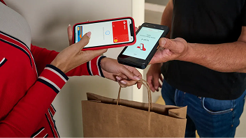 Repartidor entregando una bolsa y cobrando con el terminal