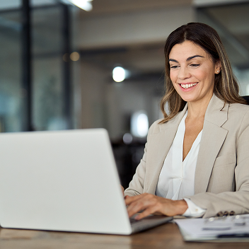 Mujer sonriente escribiendo en ordenador portátil