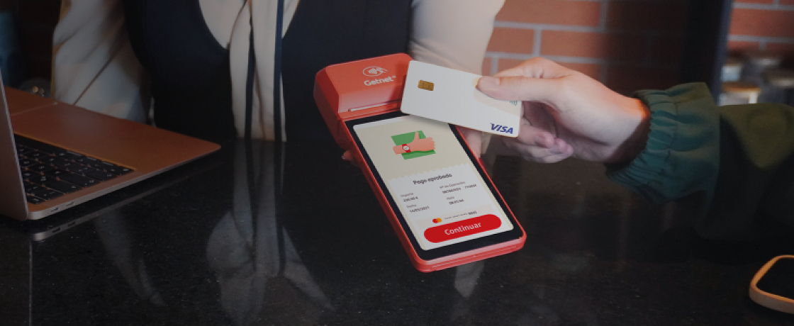Mano pasando tarjeta por TPV para pagar