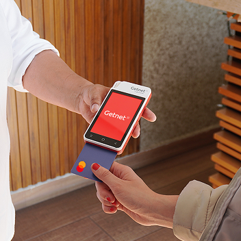 Alguien con bata sanitaria ofrece TPV y un cliente introduce la tarjeta