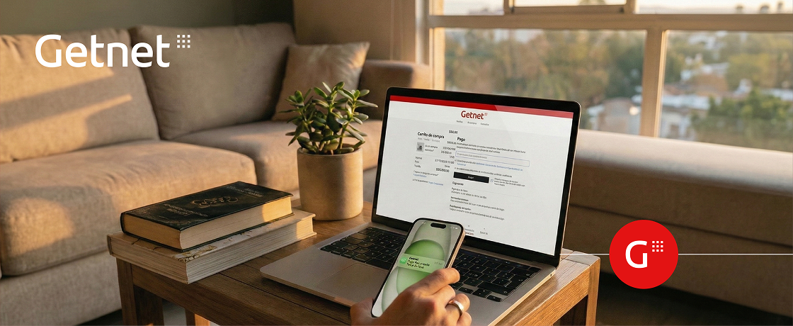 Mano con smartphone y en una mesa un laptop donde se visualiza el carrito de la compra de un sitio web