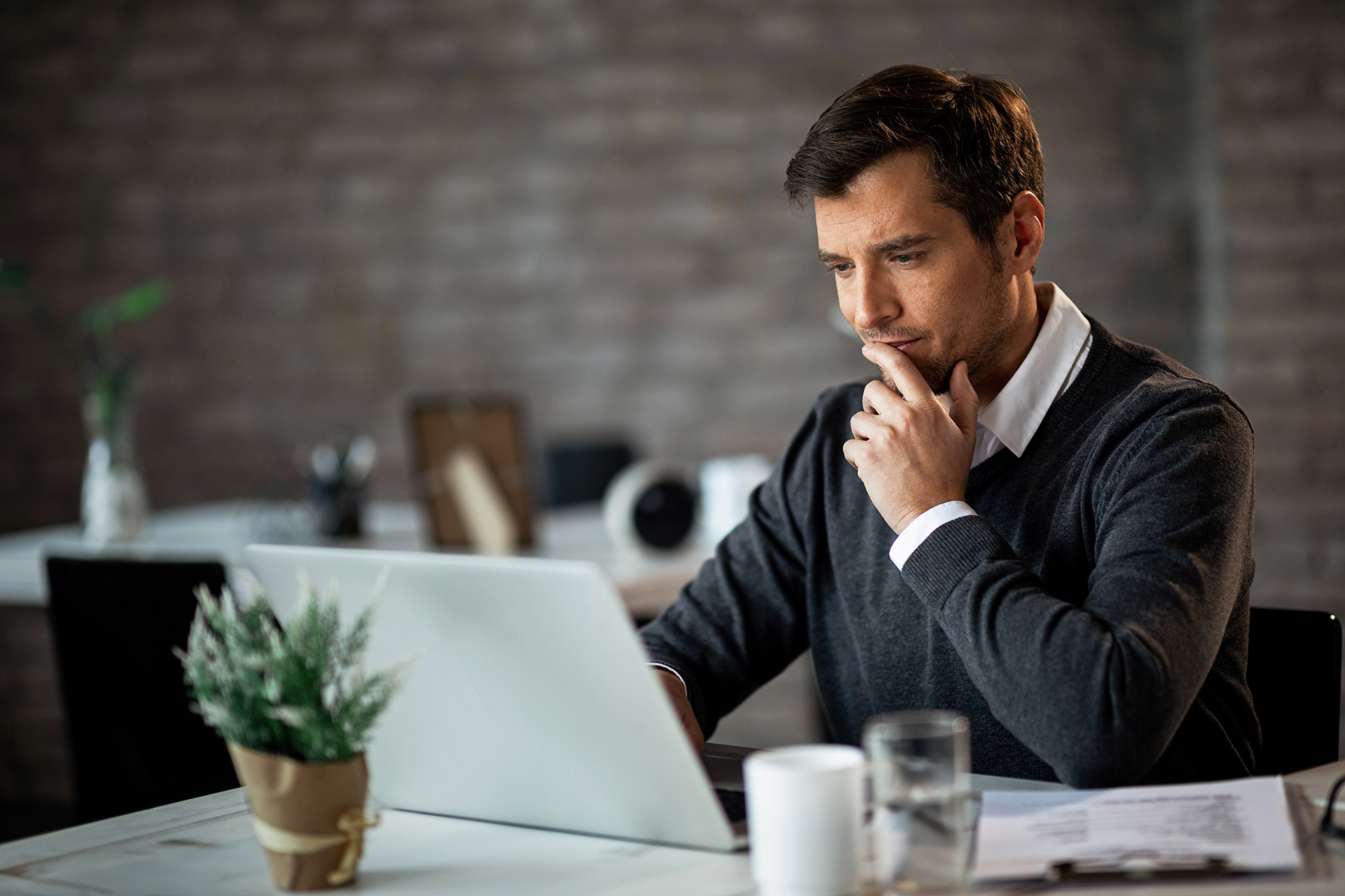 Un hombre mirando a un laptop pensativo